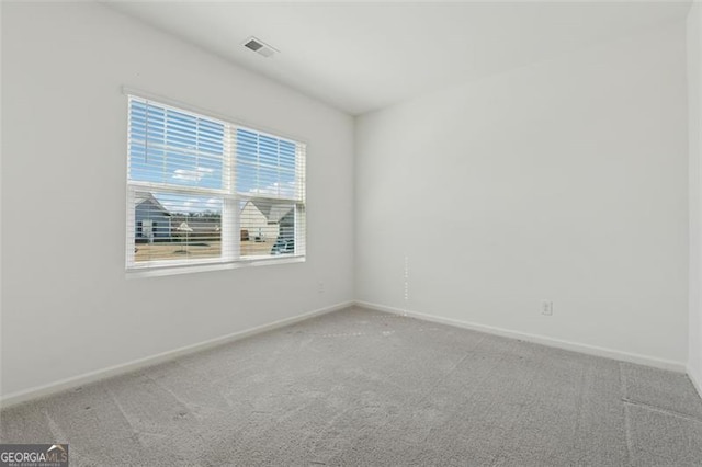 empty room featuring carpet, visible vents, and baseboards