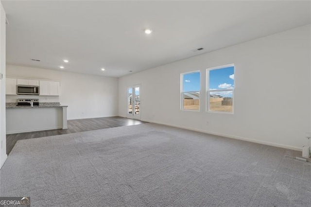 unfurnished living room with baseboards, dark colored carpet, and recessed lighting