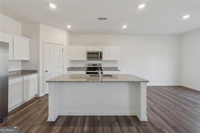 kitchen featuring visible vents, dark wood-type flooring, light stone countertops, stainless steel appliances, and a sink