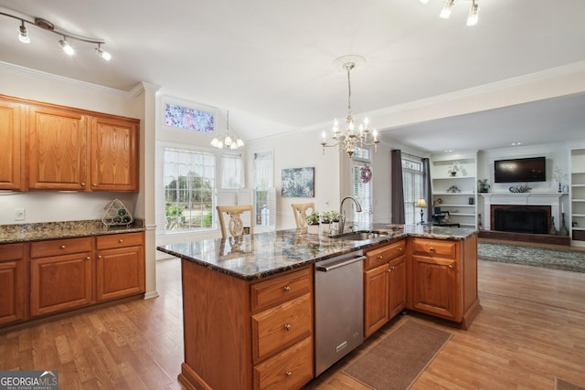 kitchen featuring a fireplace with raised hearth, stainless steel dishwasher, a sink, and light wood-style flooring