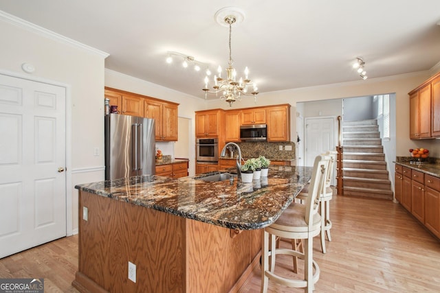 kitchen featuring stainless steel appliances, backsplash, light wood-style floors, ornamental molding, and a sink