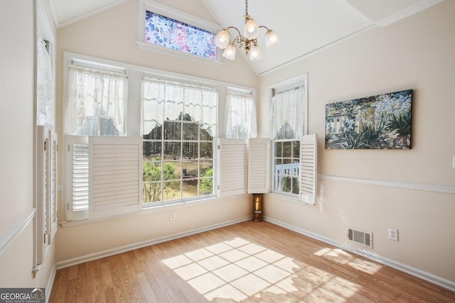 unfurnished dining area with lofted ceiling, visible vents, an inviting chandelier, and wood finished floors