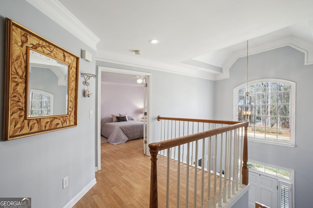 corridor with lofted ceiling, baseboards, light wood-style floors, ornamental molding, and an inviting chandelier