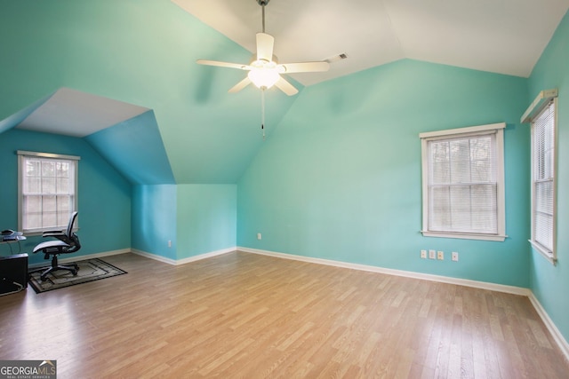 home office featuring visible vents, a ceiling fan, vaulted ceiling, wood finished floors, and baseboards