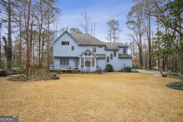 view of front of property with a deck, a chimney, and a front lawn