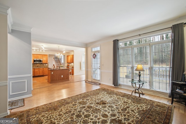 entrance foyer with an inviting chandelier, light wood finished floors, and crown molding