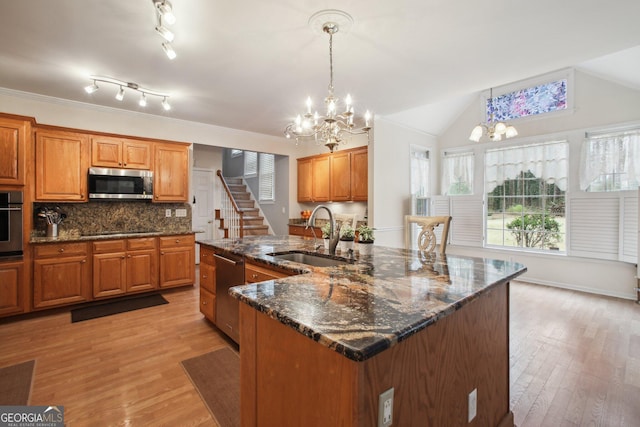 kitchen featuring stainless steel appliances, a chandelier, brown cabinets, and a sink