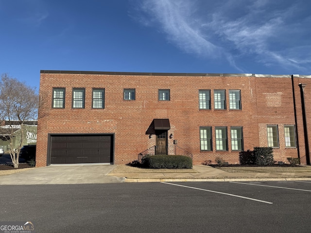 view of front of house featuring a garage, concrete driveway, and brick siding