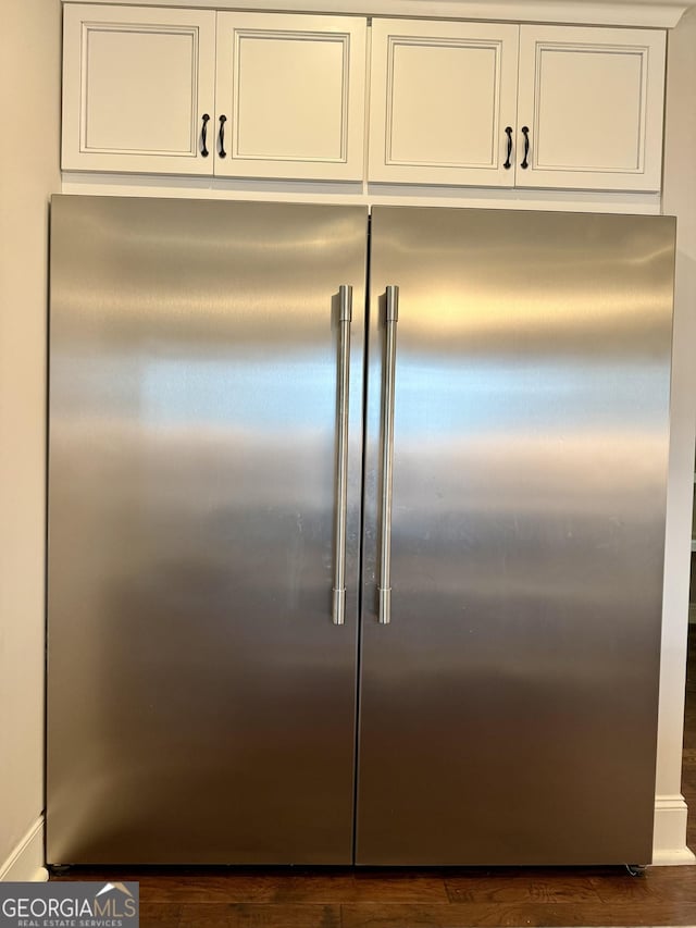 details with stainless steel built in fridge, dark wood finished floors, and white cabinetry