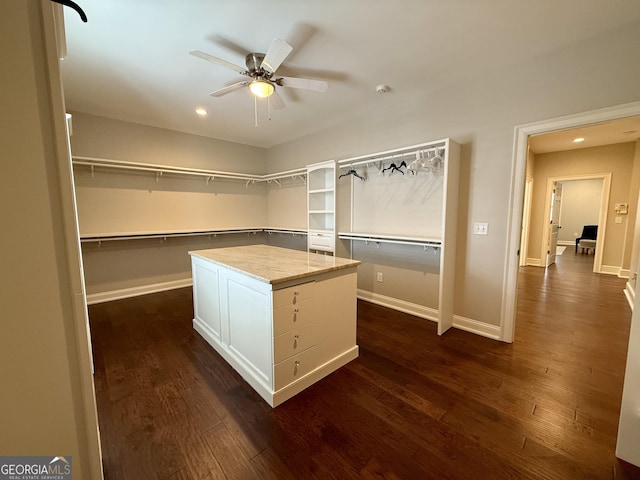 walk in closet with dark wood-type flooring and ceiling fan