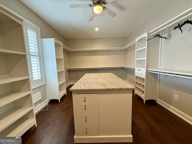 walk in closet with dark wood finished floors and a ceiling fan