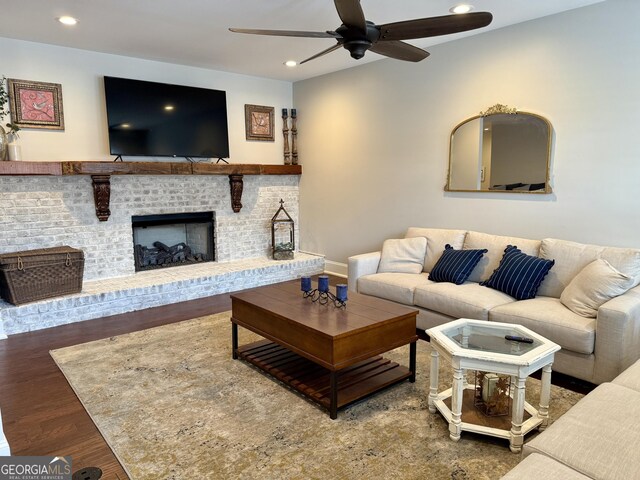 living area featuring baseboards, a ceiling fan, wood finished floors, a brick fireplace, and recessed lighting