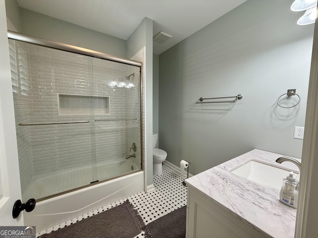 full bathroom with toilet, bath / shower combo with glass door, visible vents, vanity, and baseboards