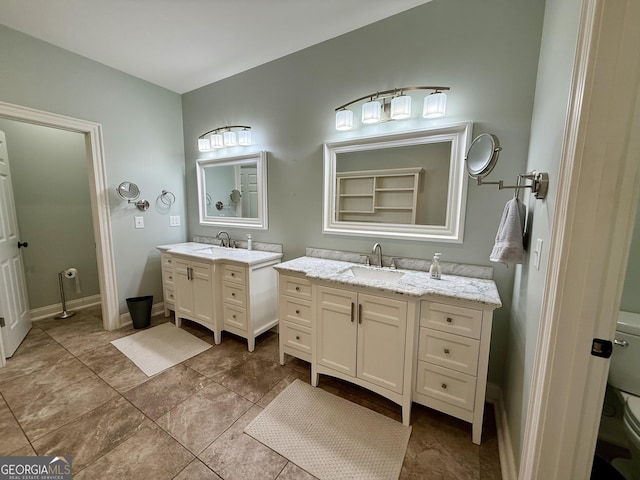 full bathroom featuring toilet, baseboards, two vanities, and a sink