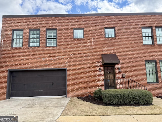 view of front of house featuring a garage, concrete driveway, and brick siding