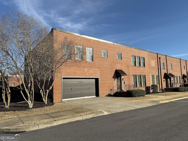 townhome / multi-family property with a garage, driveway, and brick siding