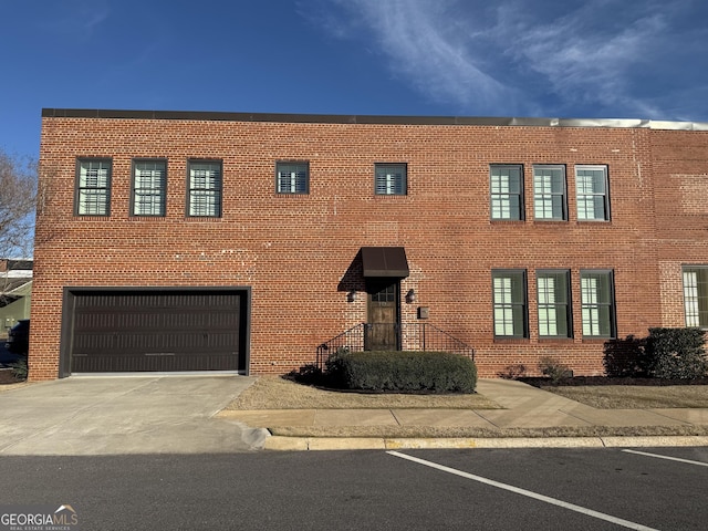 view of front of home with an attached garage, concrete driveway, and brick siding