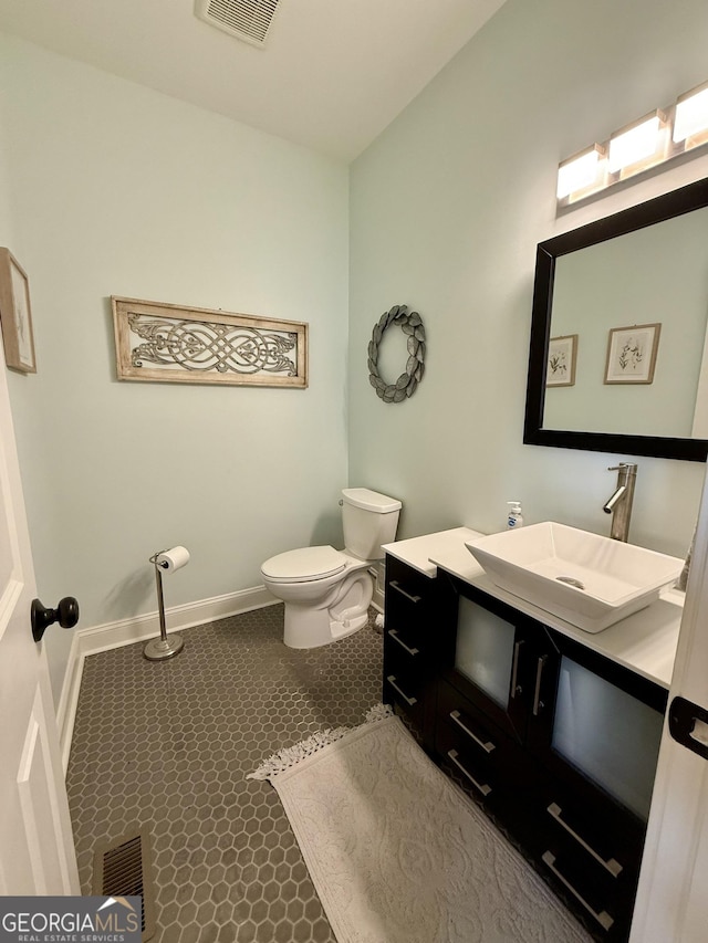 bathroom featuring toilet, baseboards, visible vents, and vanity