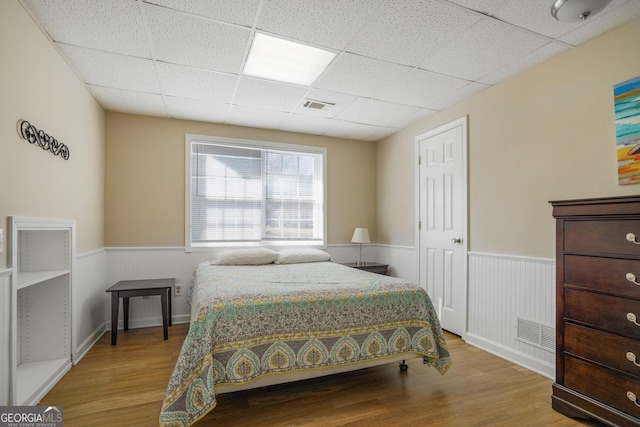 bedroom with visible vents, wood finished floors, and wainscoting