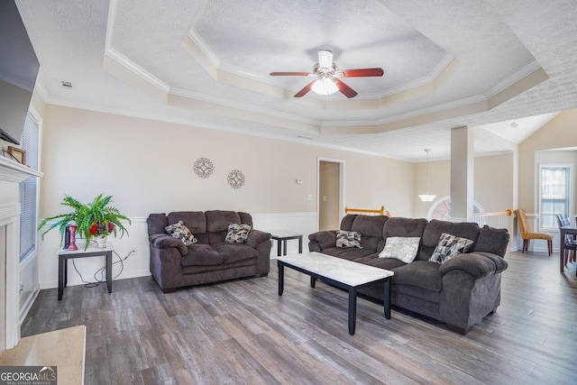 living room featuring a tray ceiling, a textured ceiling, and wood finished floors