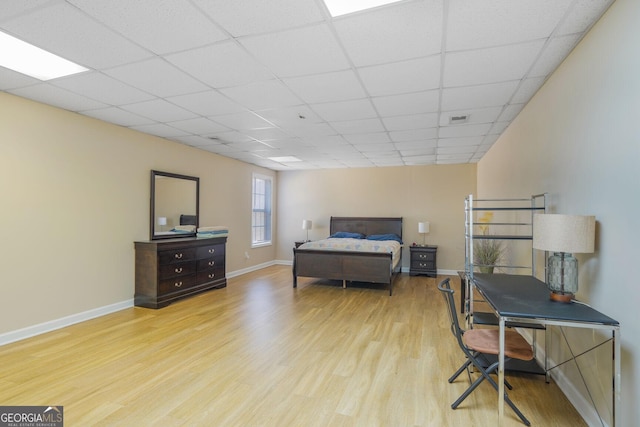 bedroom featuring a drop ceiling, wood finished floors, visible vents, and baseboards