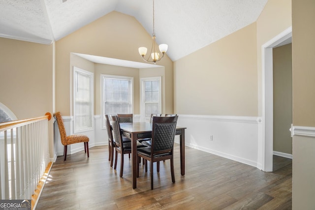 dining room with vaulted ceiling, a notable chandelier, a textured ceiling, and wood finished floors