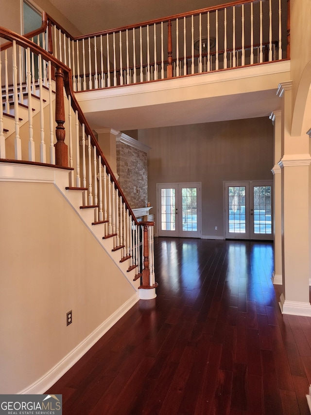 foyer entrance with french doors, decorative columns, a towering ceiling, and baseboards