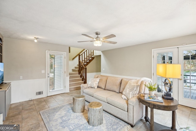 living area featuring a ceiling fan, visible vents, plenty of natural light, and stairway