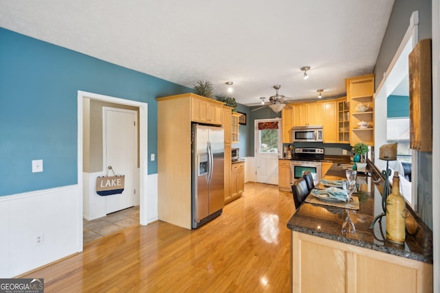 kitchen with open shelves, stainless steel appliances, light wood-style flooring, light brown cabinetry, and wainscoting