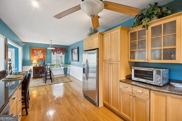 kitchen with light wood finished floors, a toaster, glass insert cabinets, light brown cabinets, and stainless steel refrigerator with ice dispenser