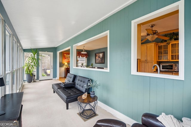 sitting room with a ceiling fan, carpet flooring, and baseboards