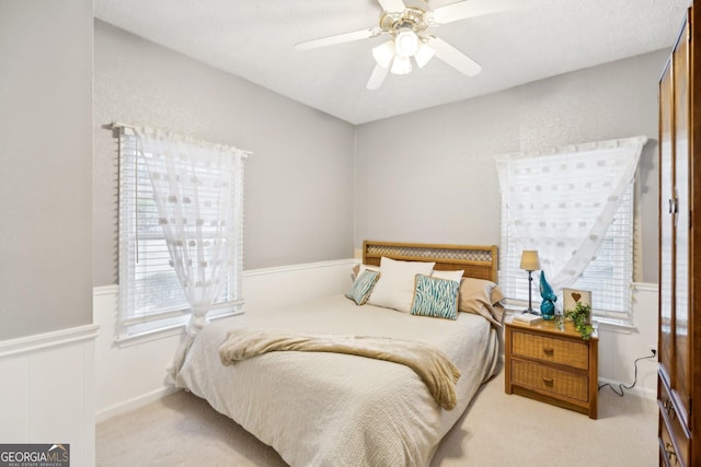 bedroom with a wainscoted wall, a ceiling fan, and carpet flooring