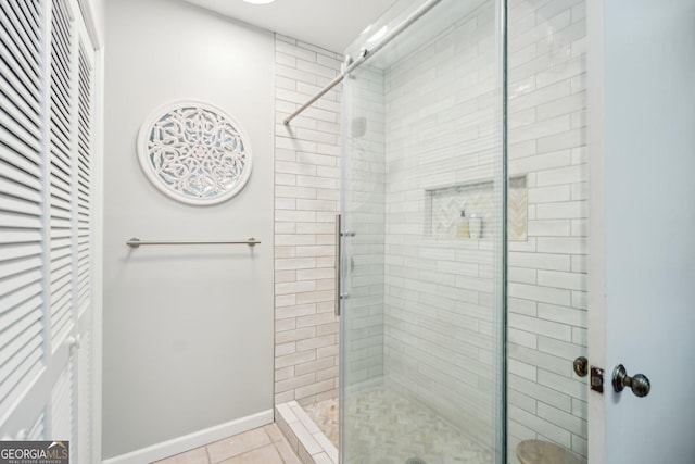 full bathroom with a stall shower, tile patterned flooring, and baseboards