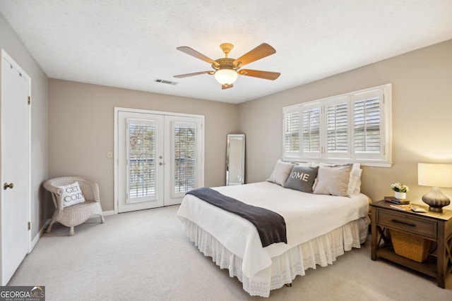 bedroom featuring light carpet, visible vents, access to exterior, a textured ceiling, and french doors