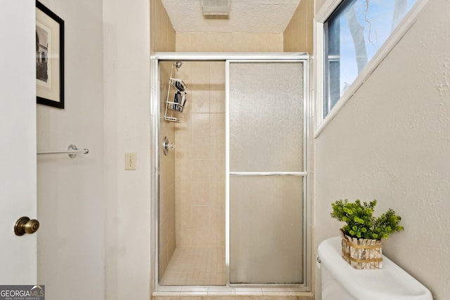 full bath featuring toilet, a stall shower, and a textured ceiling