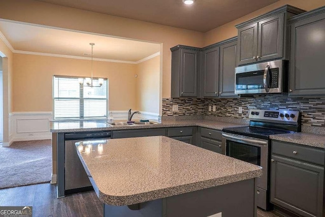 kitchen with wainscoting, ornamental molding, gray cabinets, stainless steel appliances, and a sink