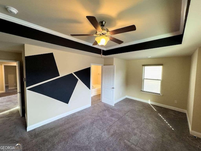 carpeted empty room featuring a tray ceiling, a ceiling fan, and baseboards