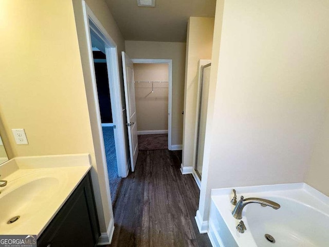 full bath with a spacious closet, a stall shower, a garden tub, and vanity