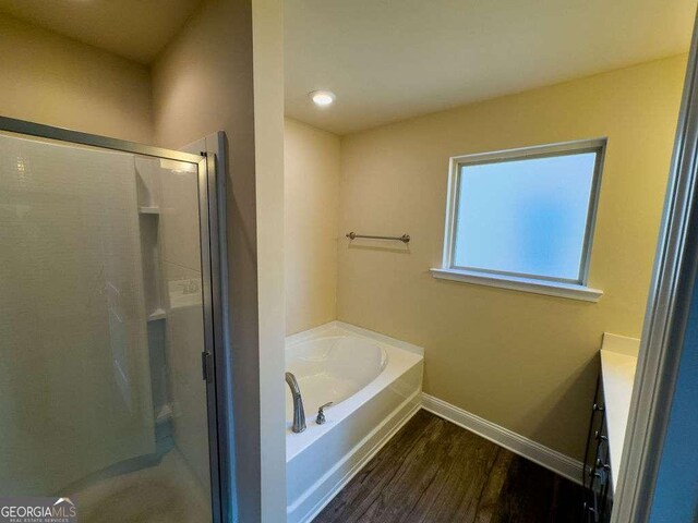 full bathroom with a garden tub, wood finished floors, vanity, baseboards, and a shower stall
