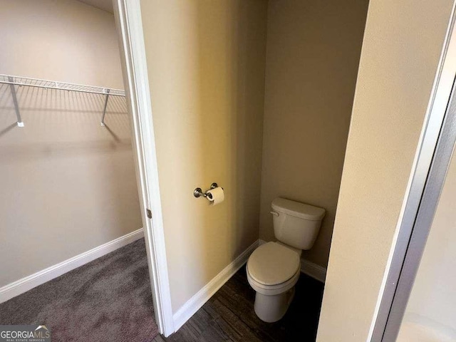 bathroom with baseboards, a spacious closet, and toilet