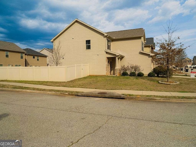 view of home's exterior featuring fence and a lawn