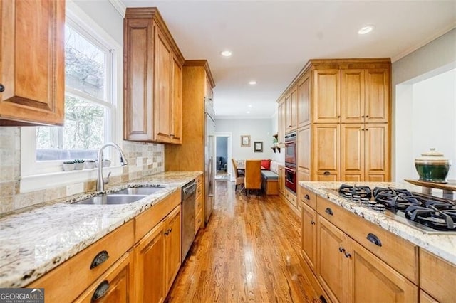 kitchen with a sink, light stone counters, tasteful backsplash, stainless steel appliances, and light wood-style floors