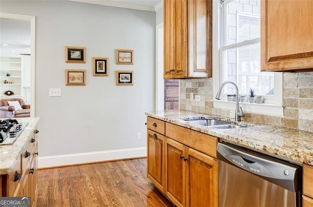 kitchen featuring stainless steel dishwasher, light stone counters, baseboards, and a sink