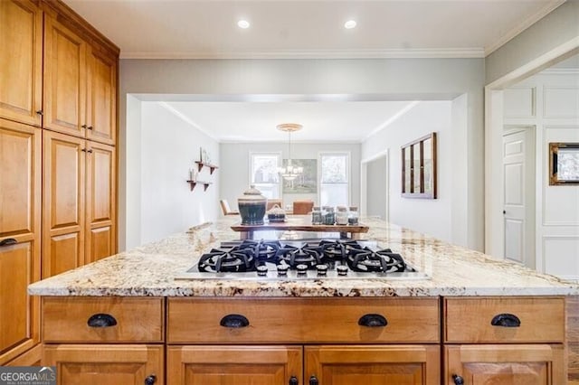 kitchen featuring brown cabinetry, light stone countertops, ornamental molding, stainless steel gas stovetop, and a notable chandelier