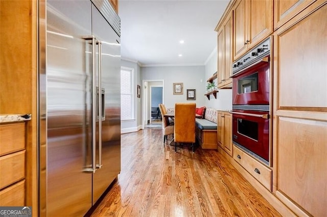 kitchen with built in refrigerator, double wall oven, recessed lighting, light wood-style floors, and crown molding