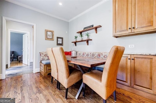 dining room featuring crown molding, baseboards, and wood finished floors