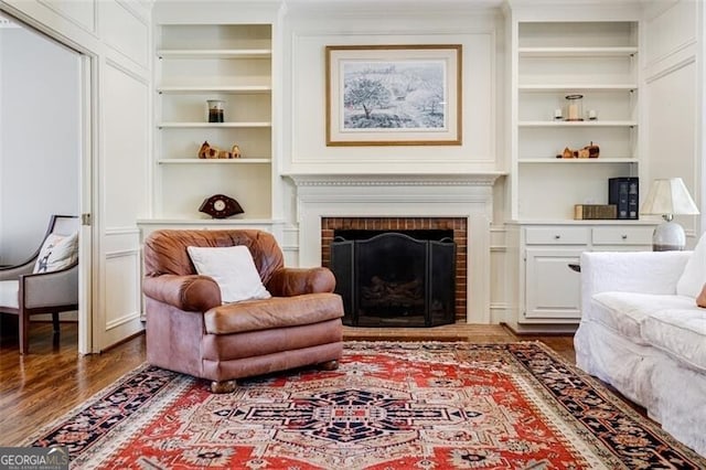 living room with built in features, wood finished floors, and a fireplace