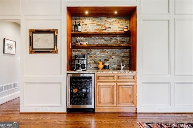 bar featuring visible vents, wine cooler, a bar, and wood finished floors