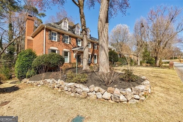 view of front facade with brick siding and a chimney