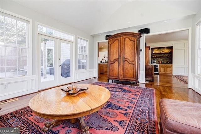 living area with visible vents, french doors, lofted ceiling, and wood finished floors